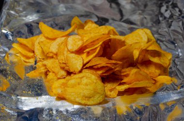 Açık folyo paketinde patates cipsi. Bir porsiyon tuzlu atıştırmalık. Yakın plan. Seçici odak.