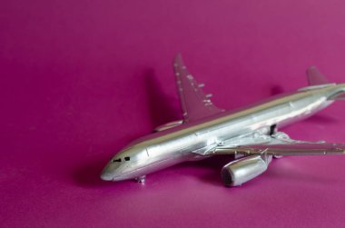 Pembe arka planda bir yolcu uçağının modeli. Gümüş uçak yaklaşıyor. Hava taşımacılığı ve turizm. Seçici odak.