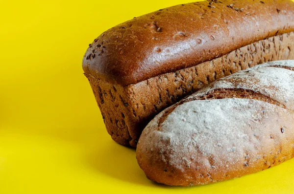 黄色背景上的两片随机的黑麦面包 示范各种自制的面包 家庭烘焙的概念 有选择的重点 — 图库照片