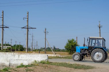 Nikolaev, Ukrayna - 15 Eylül 2020: Kırsal bir yol boyunca mavi bir traktör sürüyor. Rusça yazıt traktörün adı anlamına geliyor. Tarım mühendisliği.