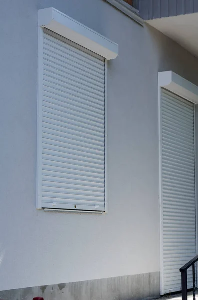 Kapalı beyaz jaluzili dükkanın önünde. Mağazanın girişi ve pencereler koruyucu alüminyum panjurlarla kapatılmış. Döküntü ve pislik yerde. Ekonomik kriz, iflas.