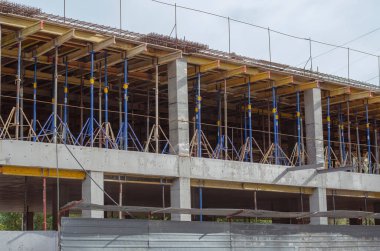 Çok katlı beton monolitik bir bina inşa ediliyor. Seviyelerden birinde birçok destek ve yük taşıyan kiriş ve sütunlar var. İnşaat alanında kimse yok..