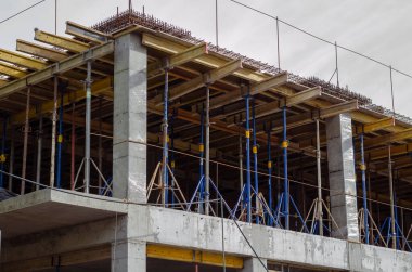 Çok katlı beton monolitik bir bina inşa ediliyor. Seviyelerden birinde birçok destek ve yük taşıyan kiriş ve sütunlar var. İnşaat alanında kimse yok..