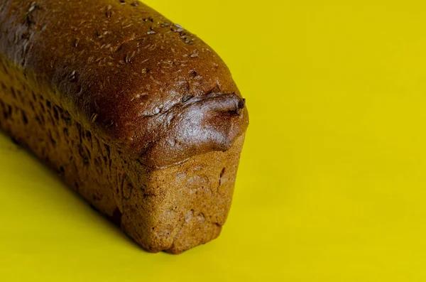 一条黑麦面包 背景为黄色 上面有香菜籽 从侧面看新鲜烘焙的自制面包 上面撒满了黄瓜籽 复制空间 有选择的重点 — 图库照片