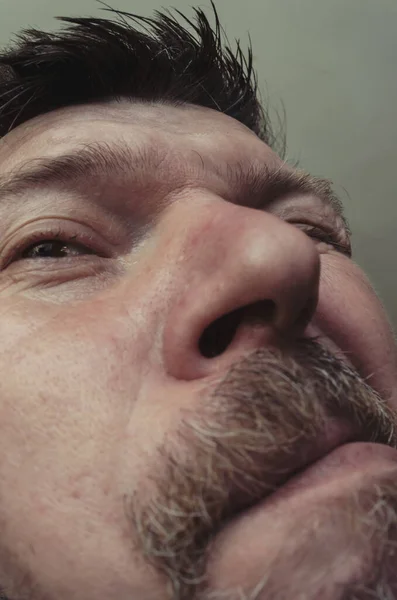 Unusual portrait of a bearded man with short brown hair. An adult man with a beard pokes his nose into the camera. Facial expressions and emotions.