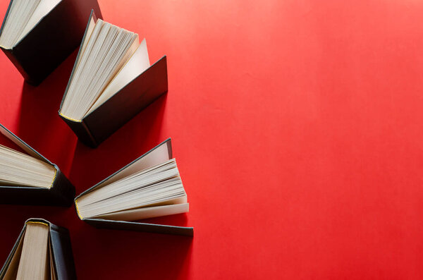 Opened hardback books on a red background. A group of books decorated in the same style. Top view from an angle. Without anyone.