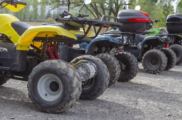 Açık hava otoparkında bir grup kirli elektrikli kuad. Off-road sürüşü için çeşitli ATV 'ler. Aktif yaşam tarzı. Turizm ve macera. Hiç kimse olmadan