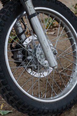 Yerde duran bir dağ motosikletinin ön tekerleği. Motosikletle off-road ve vahşi doğada seyahat et. Aktif yaşam tarzı. Hiç kimse olmadan
