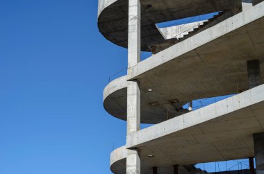Mavi gökyüzünün arka planında betondan yapılmış geometrik şekil. Modern bir alışveriş merkezinin tamamlanmamış binası. Sanayi geçmişi.