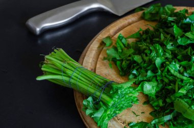 İnce dilimlenmiş çiğ yeşil kuş ve doğrama tahtasının üzerinde bir mutfak bıçağı. Bir parça kuş yaprağı. Yemek pişirmek. Seçici odak.