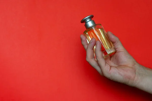 Uma Mão Segura Uma Nova Garrafa Vidro Perfume Fundo Vermelho — Fotografia de Stock