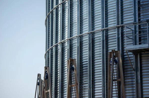 Construction of a metal grain storage. Mechanical jacks around the circumference lift the metal silo up to the top. Technology for the construction of modern granaries. Without anyone