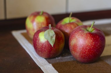 Mutfak masasındaki kırmızı elmaların çözülmüş görüntüsü. Deride bir grup elmanın yakın çekimi. Sonbahar meyve hasadı. Hiç kimse olmadan.