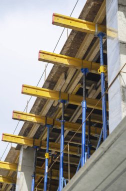 Çok katlı beton monolitik bir bina inşa ediliyor. Seviyelerden birinde birçok destek ve yük taşıyan kiriş ve sütunlar var. İnşaat alanında kimse yok..