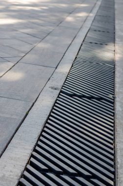 Kanalizasyon ızgaralarının soyut geometrik bileşimi. Gri kaldırım veya yolun kenarındaki sağanak yağmur hattı. Metal ızgaralar, köşegen