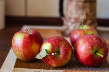 Mutfak masasındaki kırmızı elmaların çözülmüş görüntüsü. Deride bir grup elmanın yakın çekimi. Sonbahar meyve hasadı. Hiç kimse olmadan.