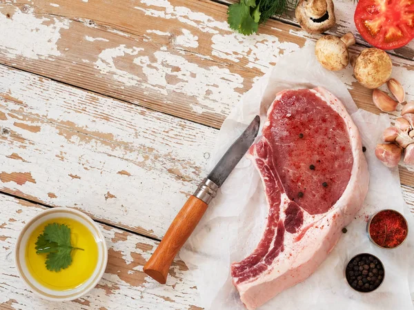 Fresh raw meat. Raw pork meat fillet with tomatoes, olive oil, spices and fresh basil on rustic wooden table. Top view flat lay background.