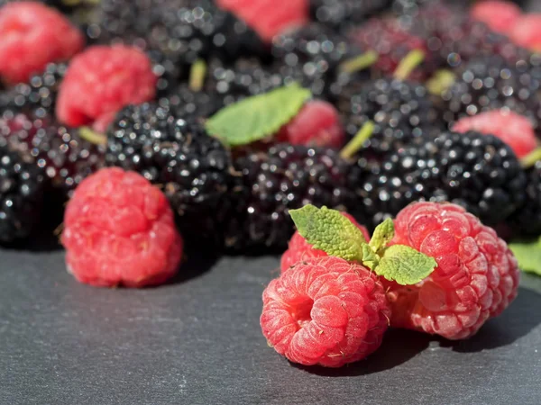 Fresh raspberry and mulberry on a dark stone background. — Stock Photo, Image