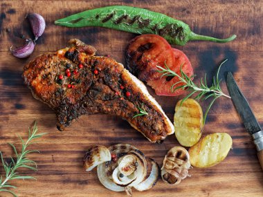 Koyu ahşap arka plan üzerinde sebze ile ızgara biftek. Üstte görüntü.