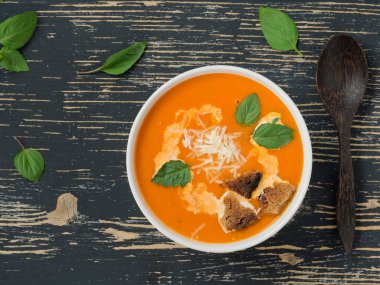 Taze domates, otlar ve zeytinyağı, fesleğen ve ekmek dilimleri ve siyah ahşap arka plan üzerinde kremso ile Domates çorbası.