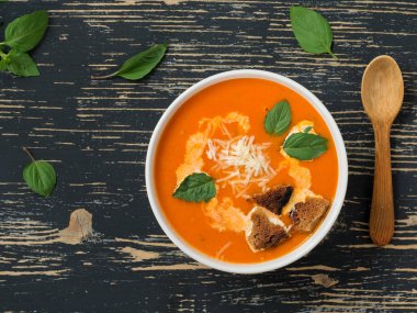 Taze domates, otlar ve zeytinyağı, fesleğen ve ekmek dilimleri ve siyah ahşap arka plan üzerinde kremso ile Domates çorbası.