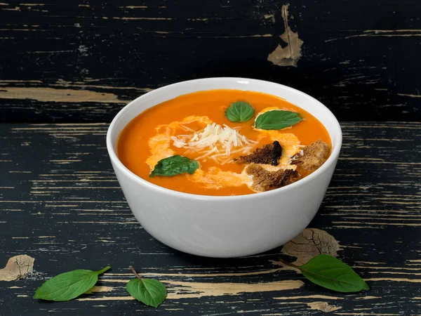 Tomatensuppe mit frischen Tomaten, Kräutern und Olivenöl, Basilikum- und Brotscheiben und cremiger Sauce auf schwarzem Holz-Hintergrund. — Stockfoto