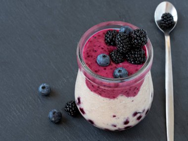 Çilek ile Smoothies: süt, kızılcık, frenk üzümü, siyah arka plan, dut, kaşık, seçici odak. Siyah taş arka plan.