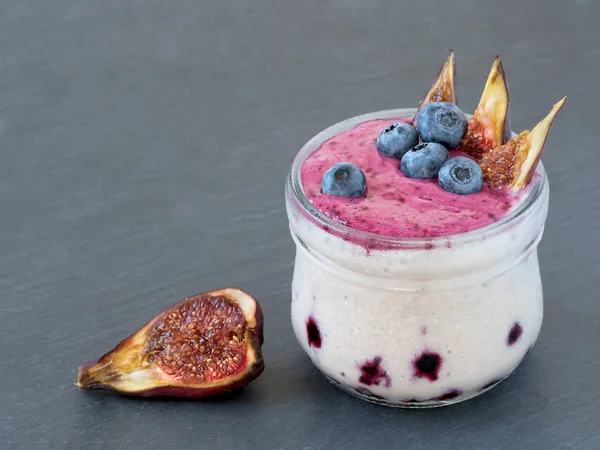 Çilek ile Smoothies: süt, kızılcık, frenk üzümü, siyah arka plan, çizgili pipetler, seçici odak. Siyah taş arka plan.