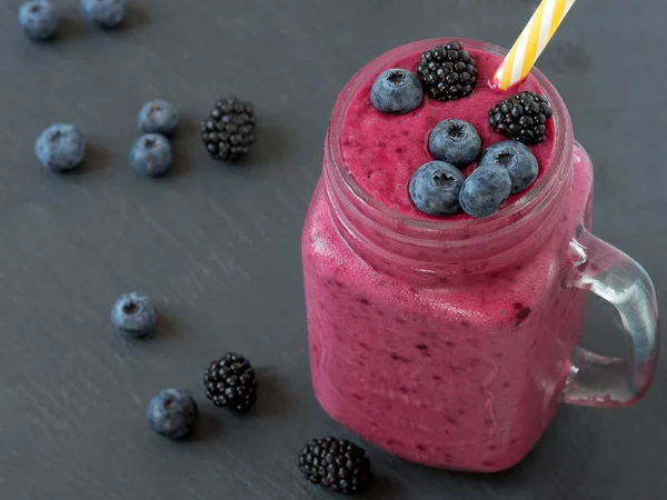 Çilek ile Smoothies: süt, kızılcık, frenk üzümü, siyah arka plan, çizgili pipetler, seçici odak. Siyah taş arka plan. — Stok fotoğraf