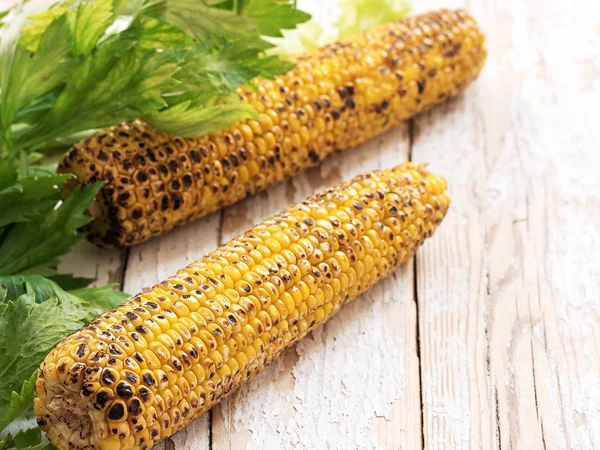 Baharat ve ızgara tereyağı ile genç Mısır. Marul yaprakları ile beyaz ahşap eski bir yüzey üzerinde yer almaktadır. Boş alan.
