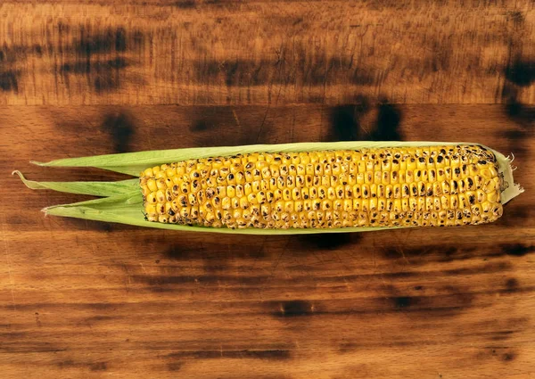 Ear of grilled young corn. Located on a wooden dark background. View from above., free space. — Stock Photo, Image