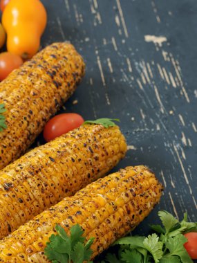 Siyah bir Vintage ahşap yüzeyde bulunan kişniş ve domates ile ızgara koçanları. Kısmi odak