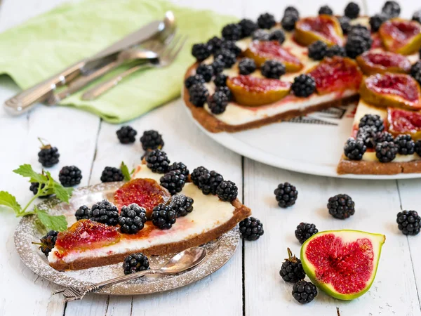 A piece of homemade pie with figs and blackberries is located on a vintage plate. Wooden vintage background. Next to a blackberry berry pie, a cut fig. Close - up. — Stock Photo, Image