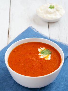 Taze domates çorbası. Mevsimlik yaz yemeği. Bir vintage beyaz arka plan üzerinde yer almaktadır. Yakında mavi kağıt havlu ve sos üzerine bir kaşık. Close.