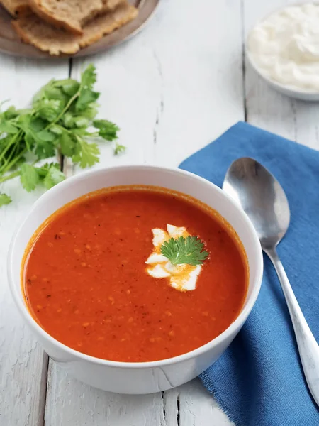 Taze domates çorbası. Mevsimlik yaz yemeği. Bir vintage beyaz arka plan üzerinde yer almaktadır. Yakınlarda mavi pamuklu peçetede bir kaşık var. Ekmek ve Sos. Close.