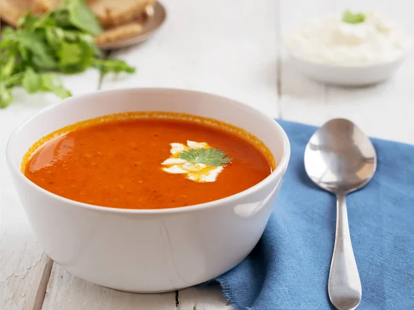 Taze domates çorbası. Mevsimlik yaz yemeği. Bir vintage beyaz arka plan üzerinde yer almaktadır. Yakınlarda mavi pamuklu peçetede bir kaşık var. Ekmek ve Sos. Close.