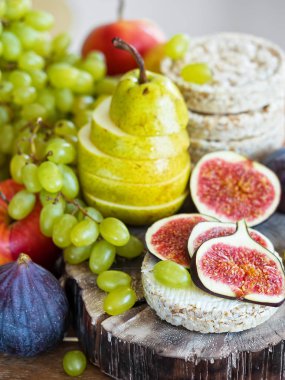 Sonbahar, taze meyveler. Ön planda dilimlenmiş incir ve ahşap bir tepsi üzerinde bulunan bir armut vardır. Close.