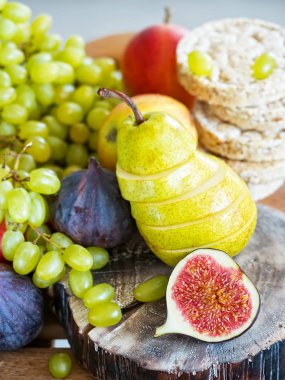 Sonbahar, taze meyveler. Ön planda dilimlenmiş incir ve ahşap bir tepsi üzerinde bulunan bir armut vardır. Close.