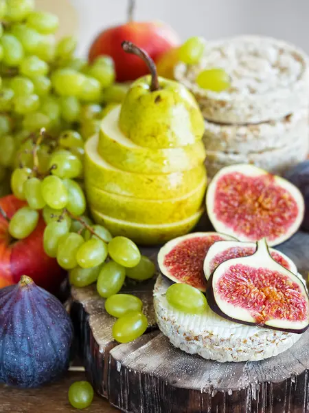 Sonbahar, taze meyveler. Ön planda dilimlenmiş incir ve ahşap bir tepsi üzerinde bulunan bir armut vardır. Close.