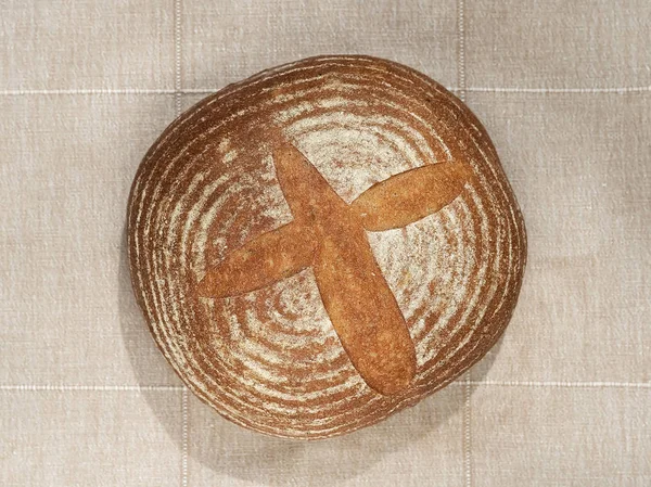 Round handmade bread, top view. Located on a gray cotton background.