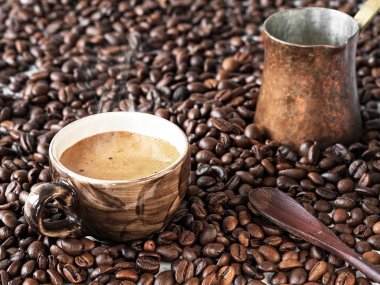 Taze demlenmiş espresso ve bakır cezve ile siyah bir fincan fasulye olduğunu. Kahve taneleri ahşap bir masaya serpiştirilir. Close. Seçici odaklama