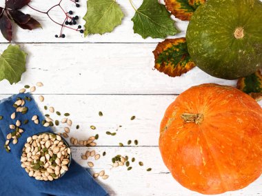 Eski ahşap bir arka planda sonbahar yaprakları ve balkabakları. Kabak çekirdekli kase. Kopya alanı olan bir arkaplan. Üst manzara, düz plan.