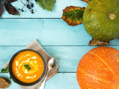 Sonbahar yaprakları, eski ahşap bir arka planda balkabakları. Kabak çorbası ve kabak çekirdekli kase. Kopya alanı olan bir arkaplan. Üst manzara, düz plan.