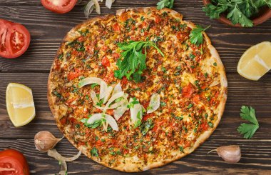 Kıymalı kuzu kıymalı Türk pizzası ve sebzeli ve otlu ince bir kabuklu sığır eti, yatay düzen. Tahta masa, üst manzara, düz yatış.