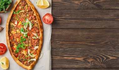 Pide, kıyma, kuzu eti, baharat ve otlarla doldurulmuş Türk sandal şeklinde bir düz ekmektir. Tahta masa, üst görünüm, düz görünüm, kopyalama alanı