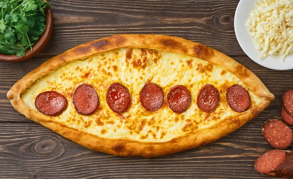 Pide - Sosisli (sudjuk) ve baharatlı Türk sandalı ekmek. Ahşap masa, üst manzara, düz uzanma