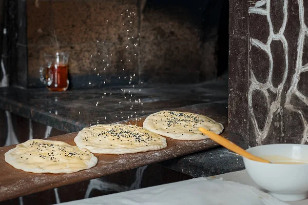 Before baking in the oven, the chef sprinkles the buns with sesame seeds. Buns for making traditional duner (Tombik Doner), oriental fast food. Close-up, copy space, traditional cuisine