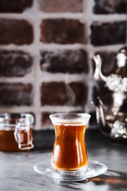 Geleneksel bir bardakta Türk kırmızı aromatik çayı - koyu tuğla zemin üzerinde armudu. Buhar çay bardağının üzerine yükselir. Yakın plan, sığ alan derinliği, kopyalama alanı