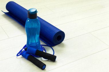 Eğitim ve dinlenme kavramı. Yoga minderinin üstündeki atlama ipinin yanında şişe ya da su. Spor ve Sağlık