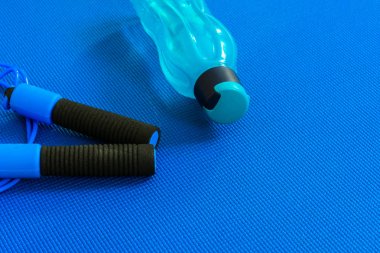 Yoga minderinin üstündeki atlama ipinin yanında şişe ya da su. Eğitim ve dinlenme kavramı. Spor ve Sağlık